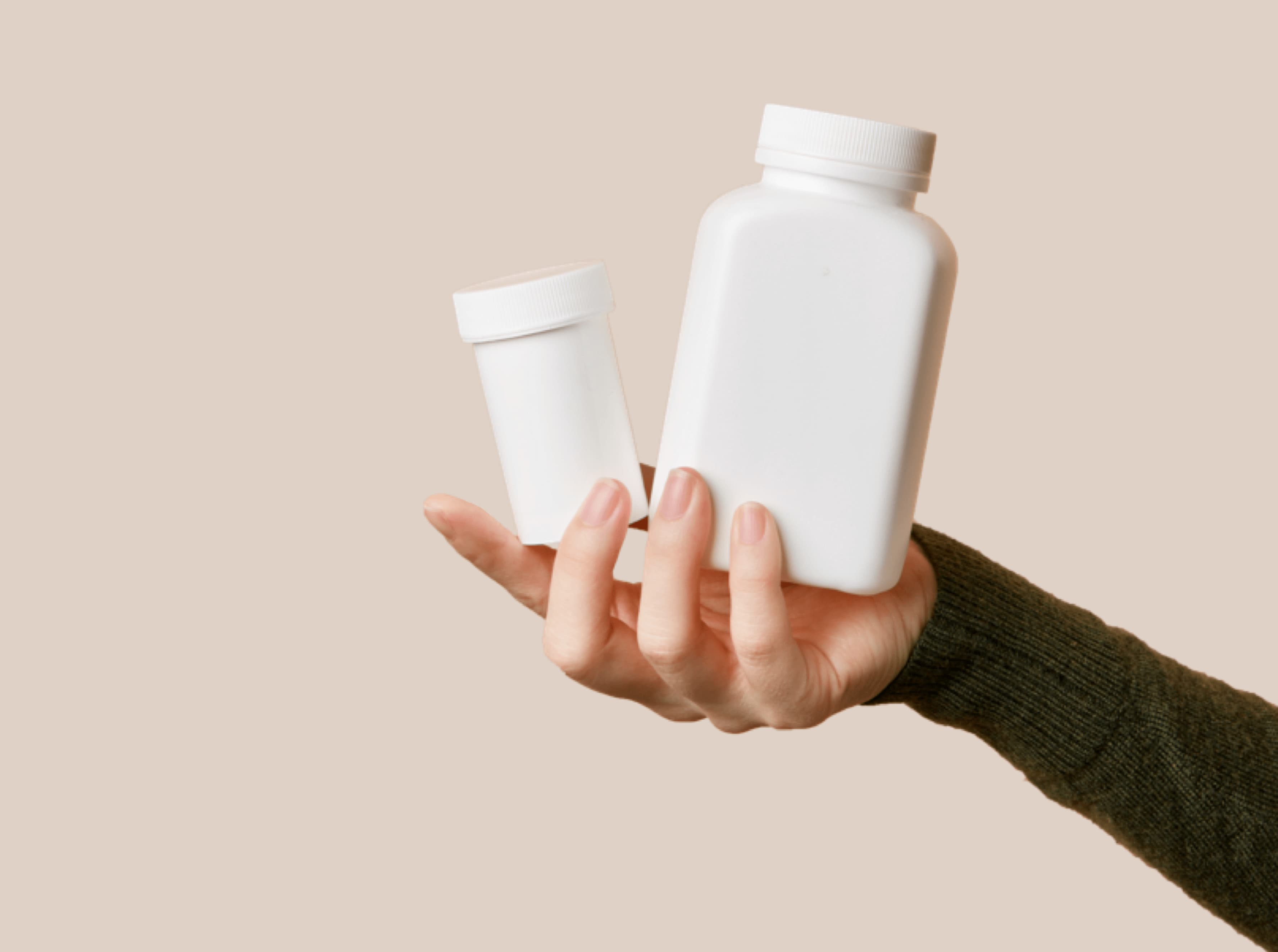 Hand holding white pill bottles.